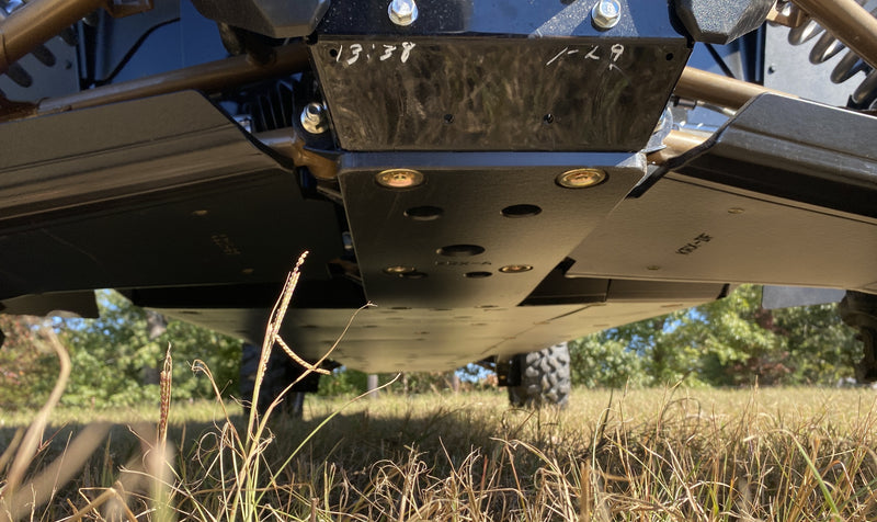 Trail Armor black full skid plates ground-level underside view on Kawasaki KRX 4 1000 outdoor field