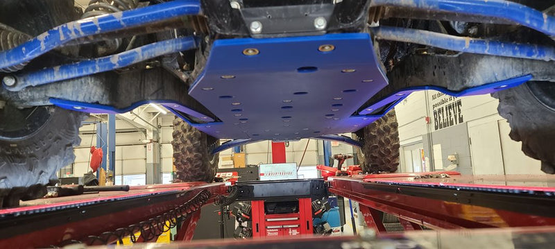 Trail Armor blue skid plate undercarriage view installed on Kawasaki KRX 1000 in shop