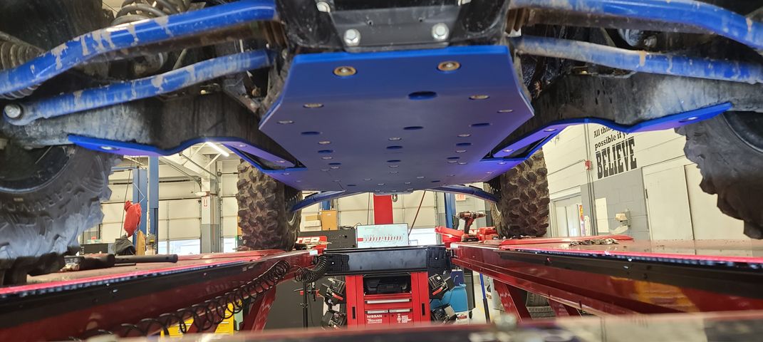 Trail Armor blue skid plate undercarriage view installed on Kawasaki KRX 1000 in shop